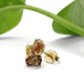 Close-up of 14kt yellow gold andalusite stud earrings with green leaf accent