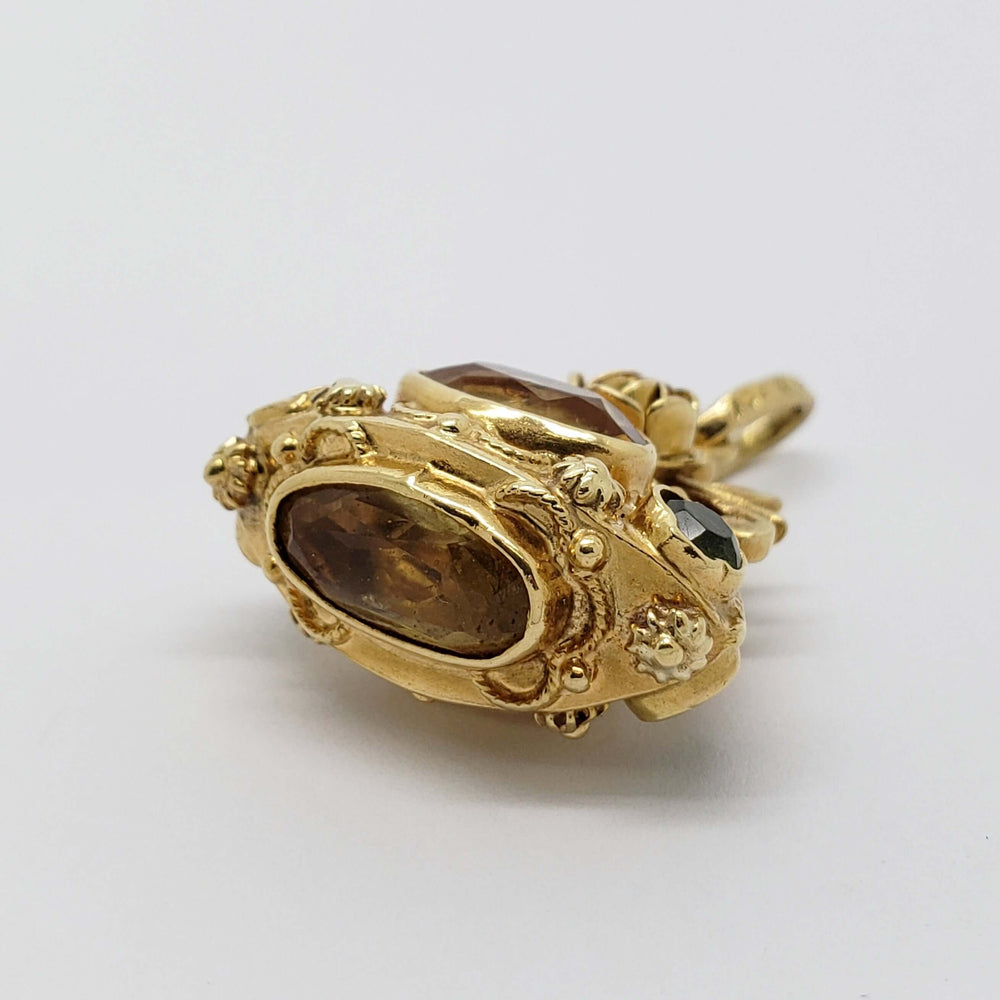 Close-up of antique 18kt yellow gold pendant featuring an oval citrine and round peridot