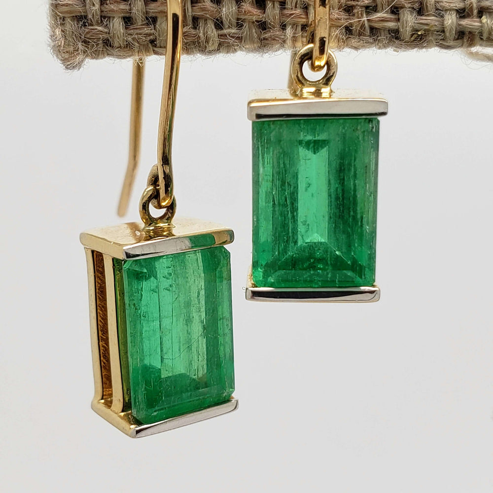 Close-up of vintage emerald and 14kt yellow gold dangle earrings on stand