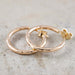Close-up of hammered 14K yellow gold hoop earrings on a stone surface