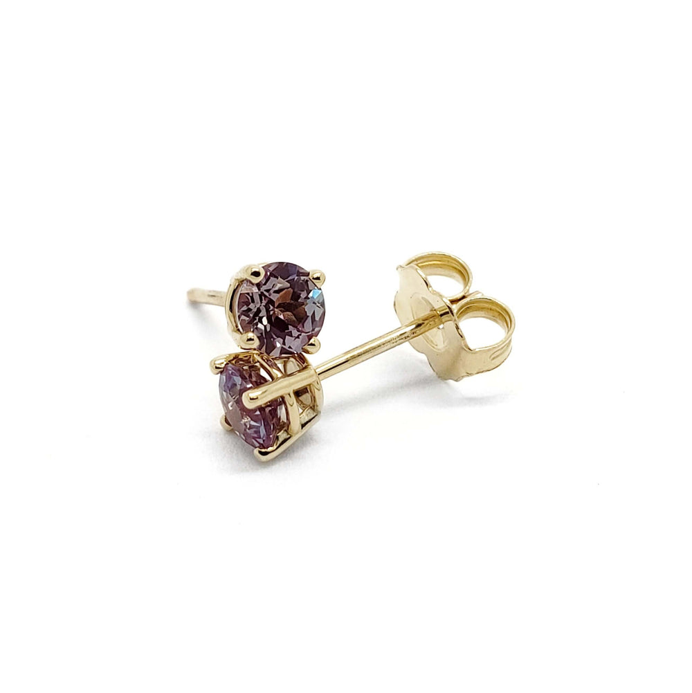 Close-up of 14k yellow gold lab-grown alexandrite stud earrings with butterfly backs