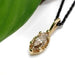 Close-up of marquise champagne diamond pendant in 14kt yellow gold next to a green leaf