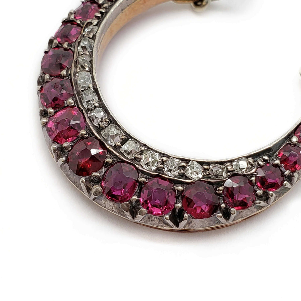 Close-up of Victorian crescent pendant featuring cushion cut rubies and diamonds in silver setting.