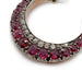 Close-up of Victorian crescent pendant featuring cushion cut rubies and diamonds in silver setting.