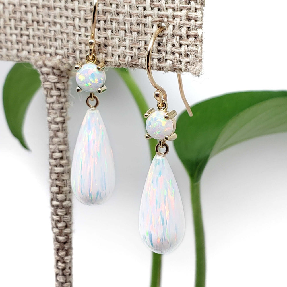 Close-up of simulated opal dangle earrings in 14kt yellow gold on display