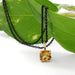 Cushion citrine pendant in yellow gold on black chain, styled on green leaf