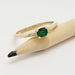 Cushion cut emerald yellow gold ring resting on a pencil