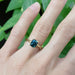 Cushion cut green sapphire engagement ring in yellow gold shown on hand