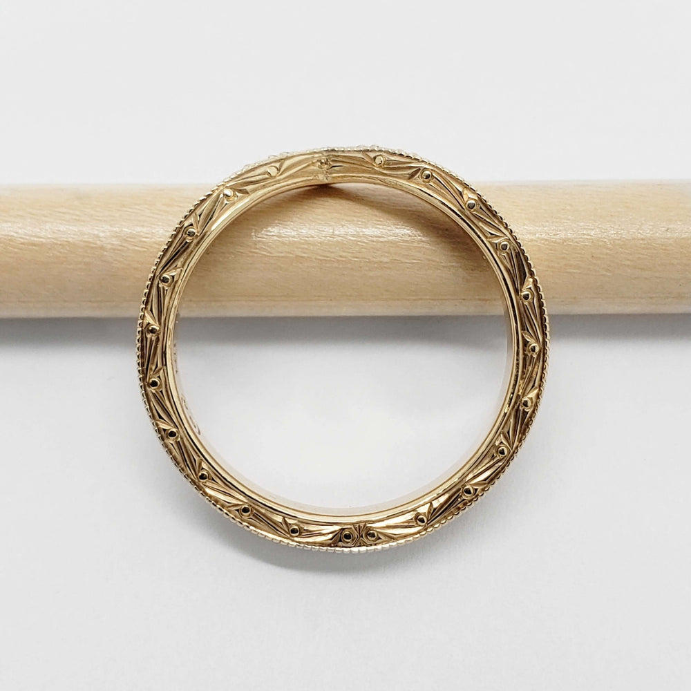 Detailed view of engraved and millgrain edges on 14kt yellow gold chevron wedding ring