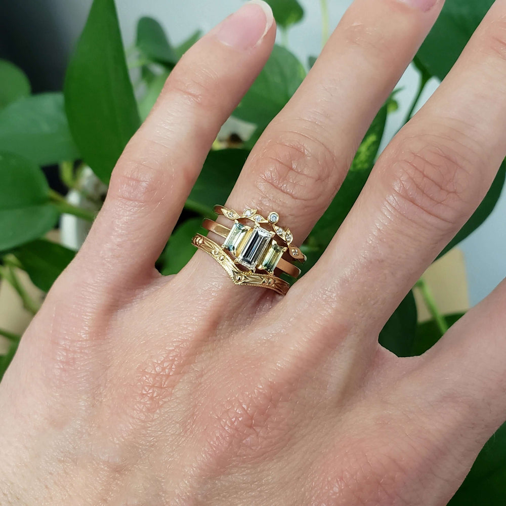 14kt yellow gold diamond and sapphire ring stacked with two gold bands on a hand