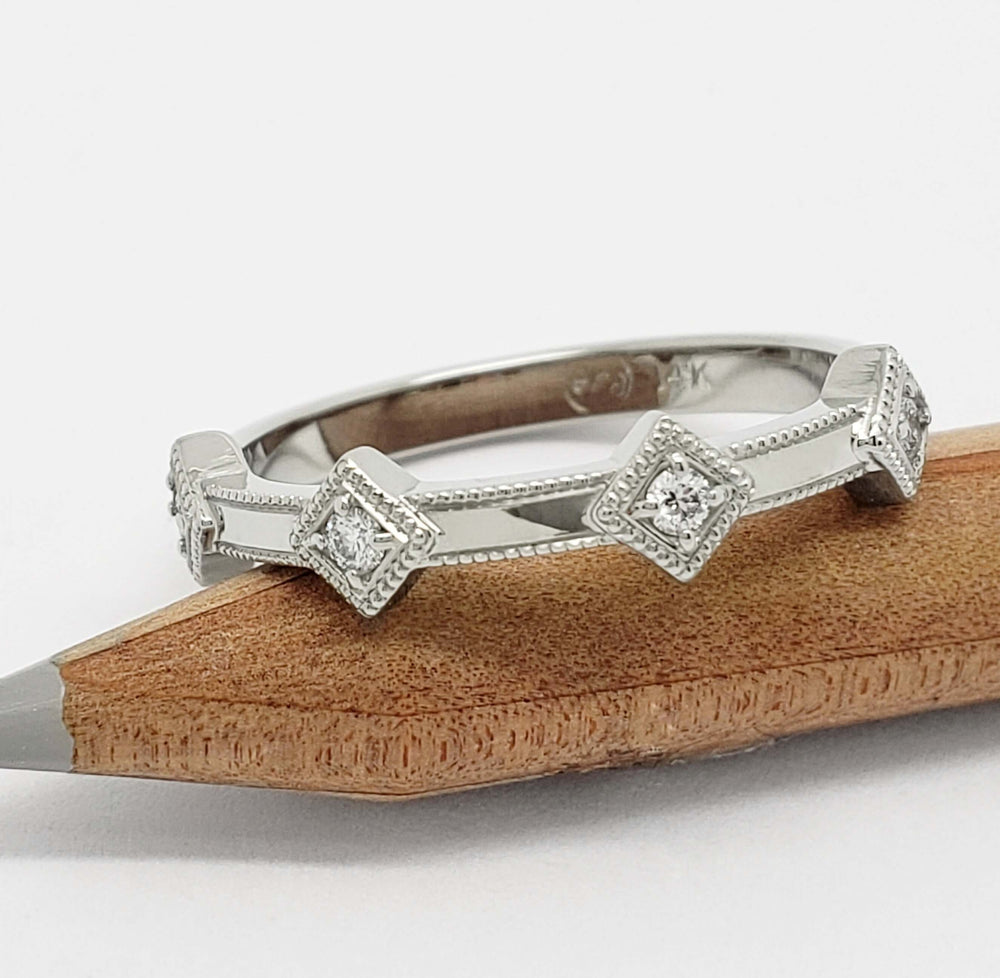 14kt white gold diamond millgrain wedding band resting on a pencil