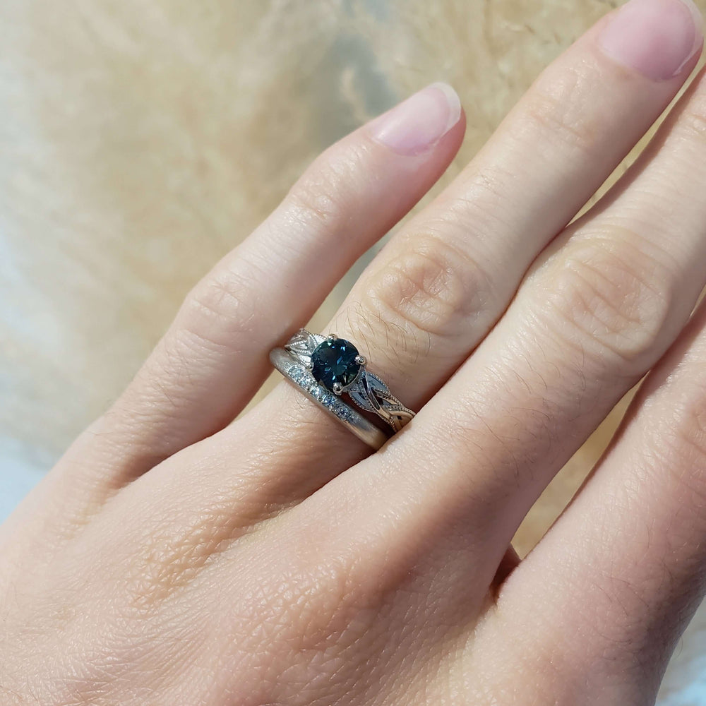 Diamond wedding ring stacked with a sapphire engagement ring on hand