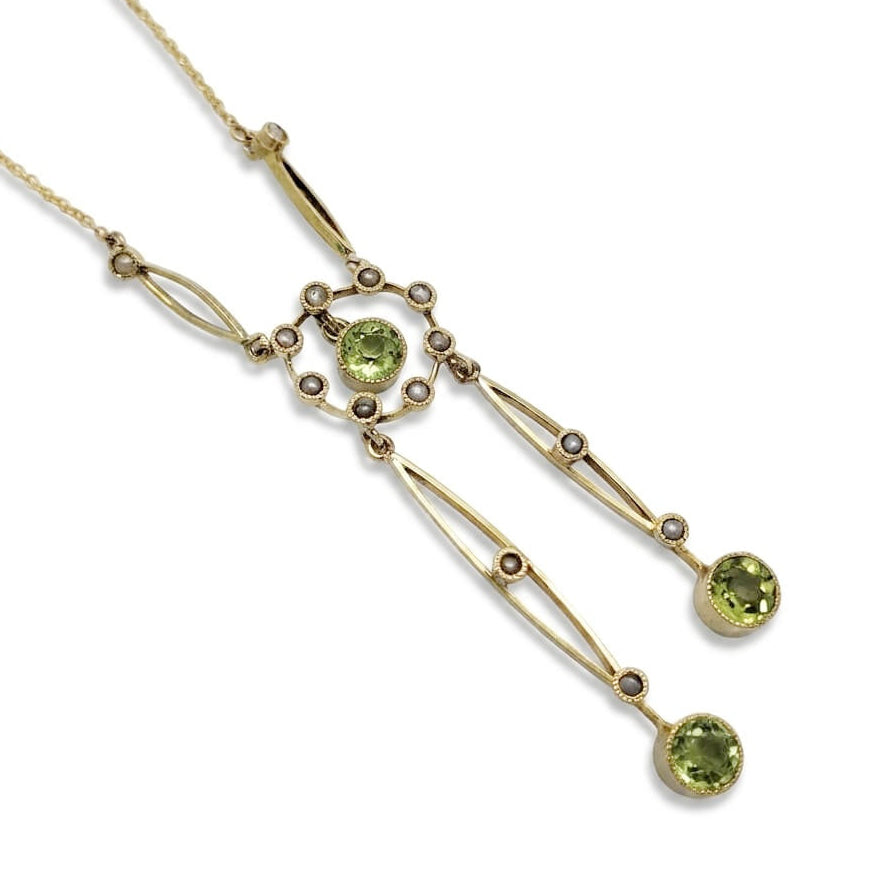 A gold necklace with a geometric Art Deco style pendant featuring round green gemstones, displayed on a clean white background.