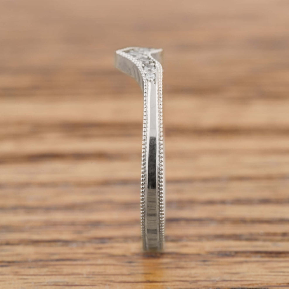 Edge view of 14k white gold chevron wedding band with millgrain detail