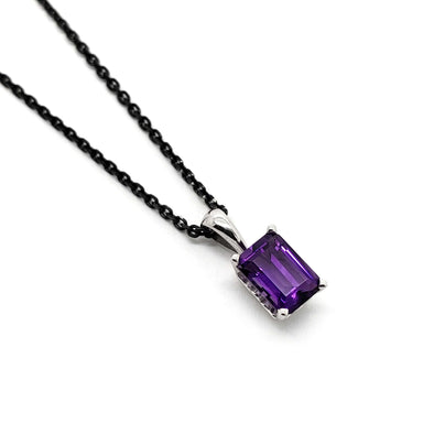 Emerald cut amethyst pendant in 14kt white gold on a black chain, angled view