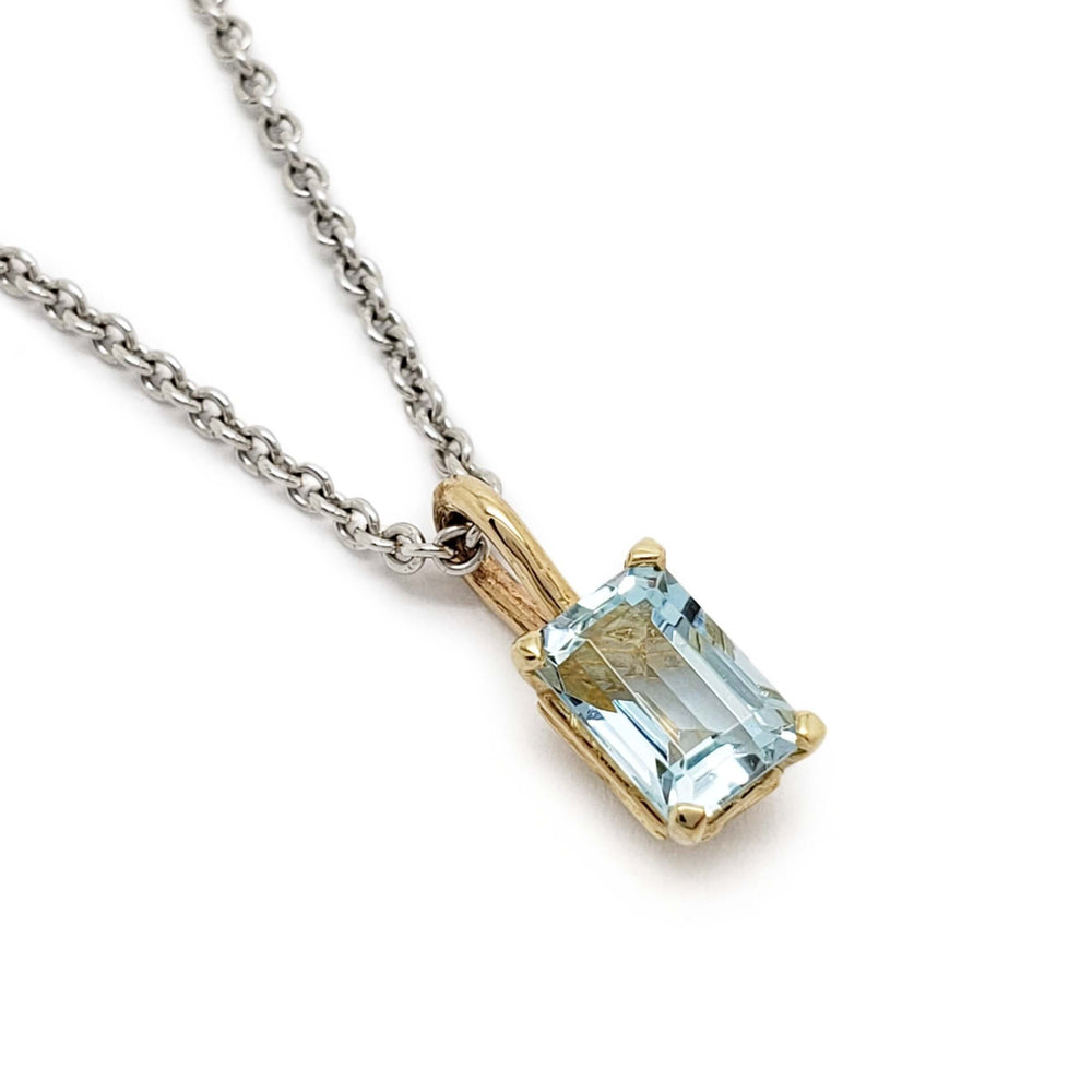 Emerald cut aquamarine pendant in 10kt yellow gold on a silver chain, close-up view