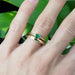 Emerald engagement ring stacked with gold bands on a hand