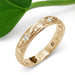 Engraved 14k yellow gold wedding band with flush-set diamonds, leaf background