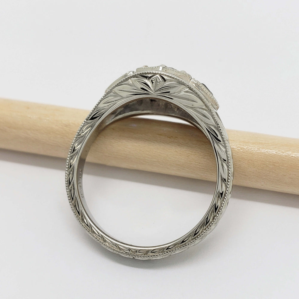 Detailed engraving on the band of a 14kt white gold ring with blue sapphires and lab diamond