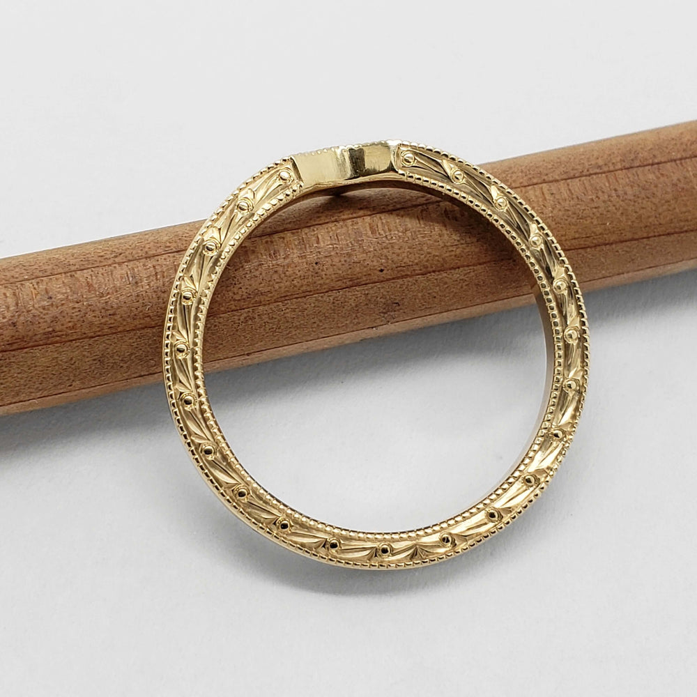 Detailed engraving on the side of a 14k yellow gold chevron wedding band