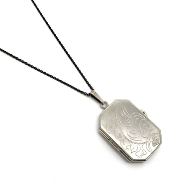 Engraved vintage sterling silver locket on a black chain, closed front view