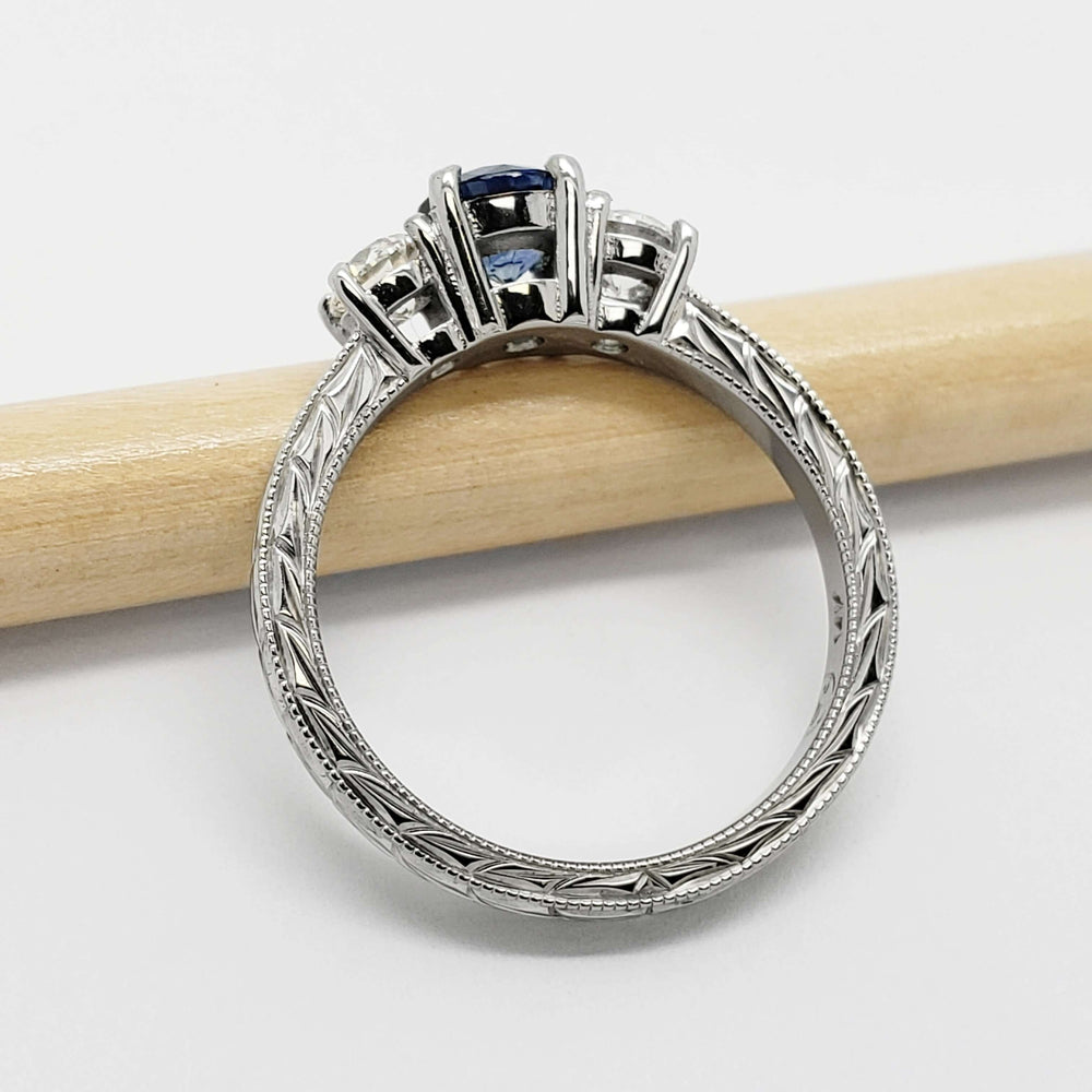 Engraved white gold band with three-stone sapphire and diamond setting, side view