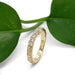 Engraved yellow gold chevron ring with lab diamonds displayed against a leaf background