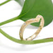 Engraved yellow gold chevron wedding ring with diamonds, styled on a green leaf