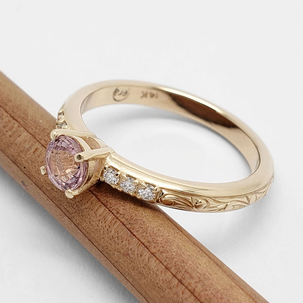 Engraved yellow gold ring with pink sapphire and diamonds, side view on pencil