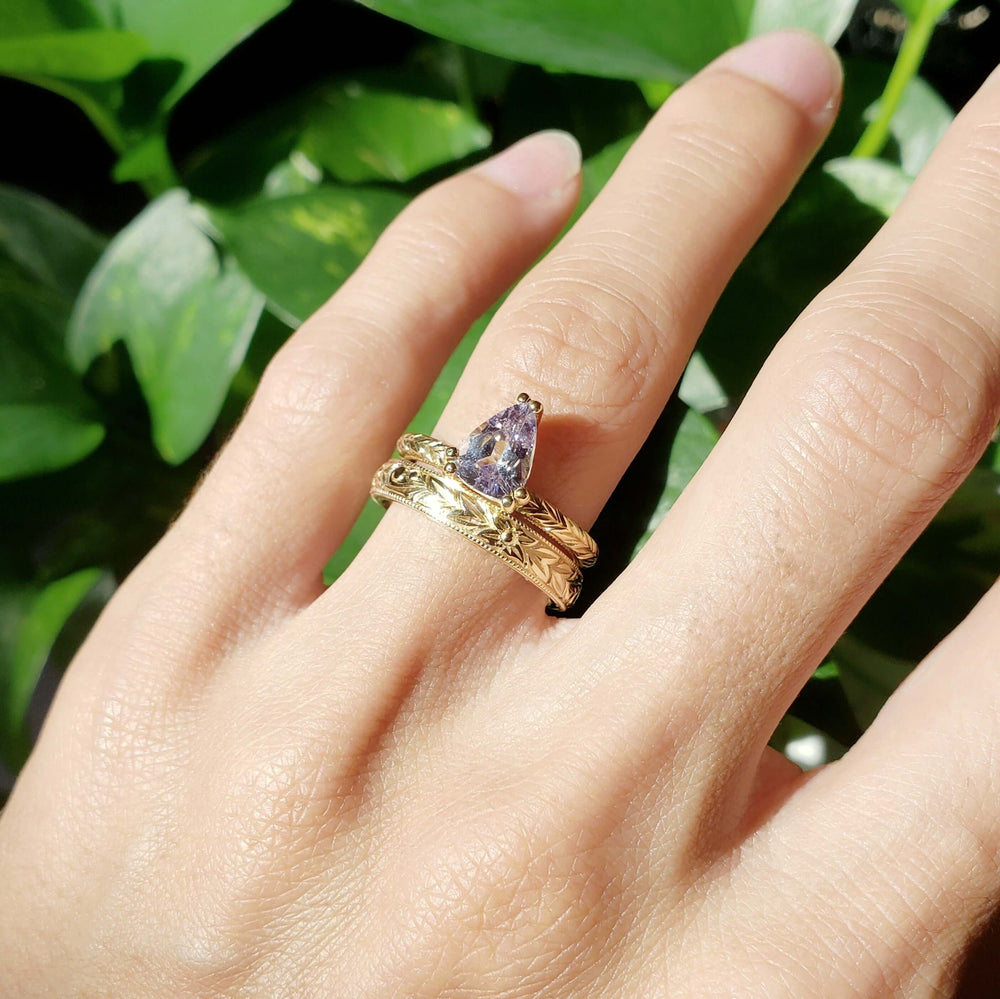 Engraved yellow gold wedding band stacked with a pear-shaped gemstone ring