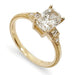 A yellow gold ring featuring a cushion-cut diamond center stone with baguette and round accent diamonds on a white background.