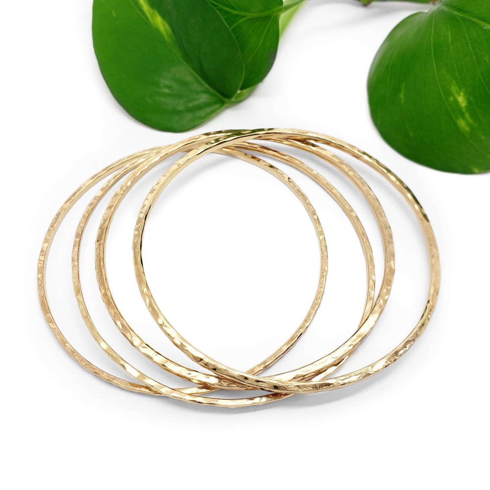 Five hammered 14kt yellow gold bangles arranged with green leaves