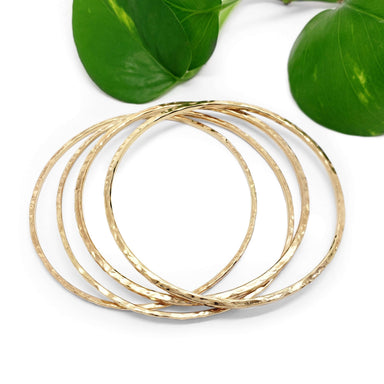 Five hammered 14kt yellow gold bangles arranged with green leaves