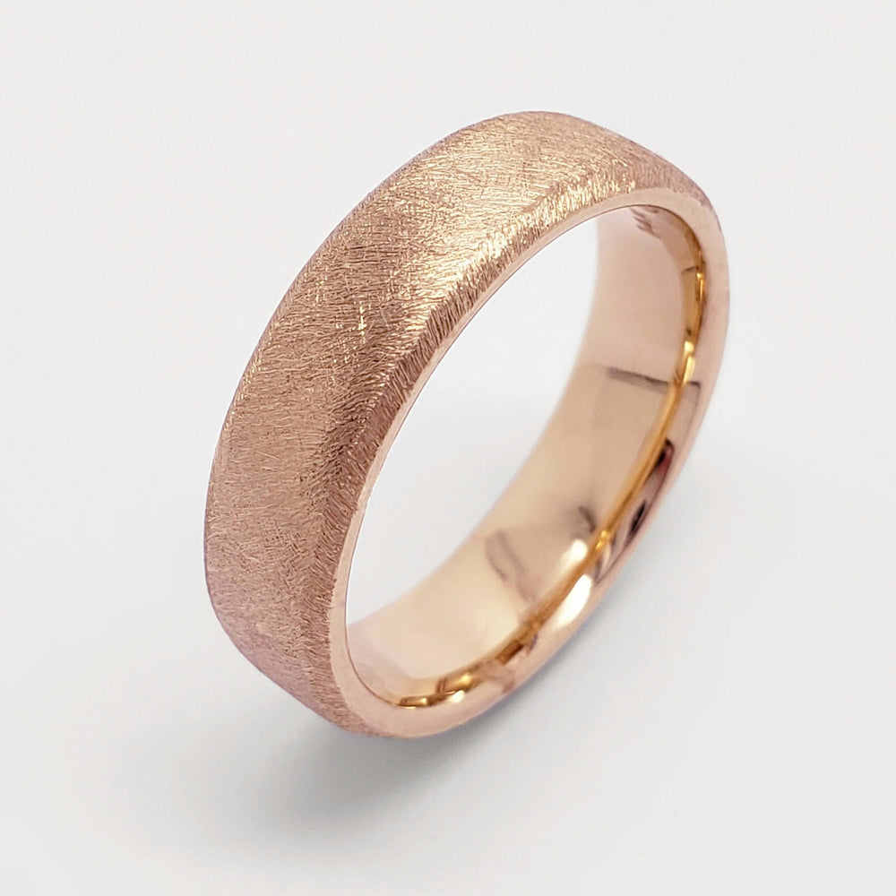 Flat 14kt rose gold wedding band with rolled edge and saw blade finish on white background