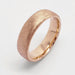 Flat 14kt rose gold wedding band with rolled edge and saw blade finish on white background