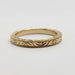 Flat lay of 14kt yellow gold wedding ring featuring engraved Salal leaf and berry motif and millgrain