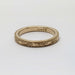 Flat lay of 14kt yellow gold wedding ring with detailed scroll engraving and millgrain