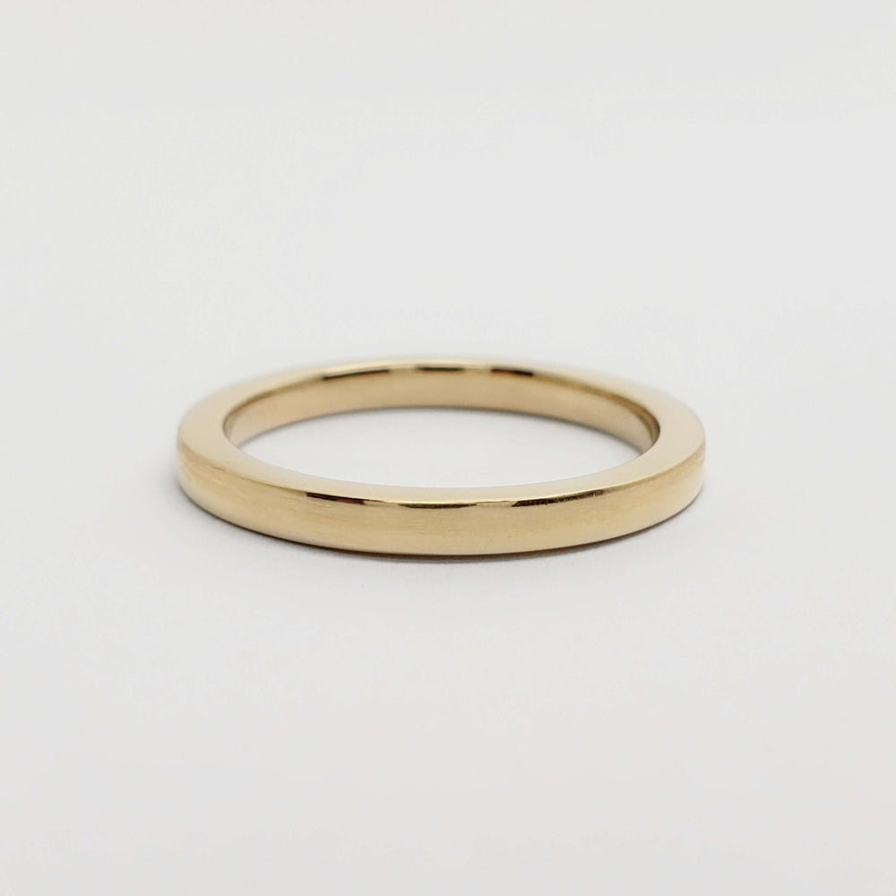 Flat profile 14kt yellow gold wedding band on white surface