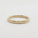 Flat profile 14kt yellow gold wedding band on white surface