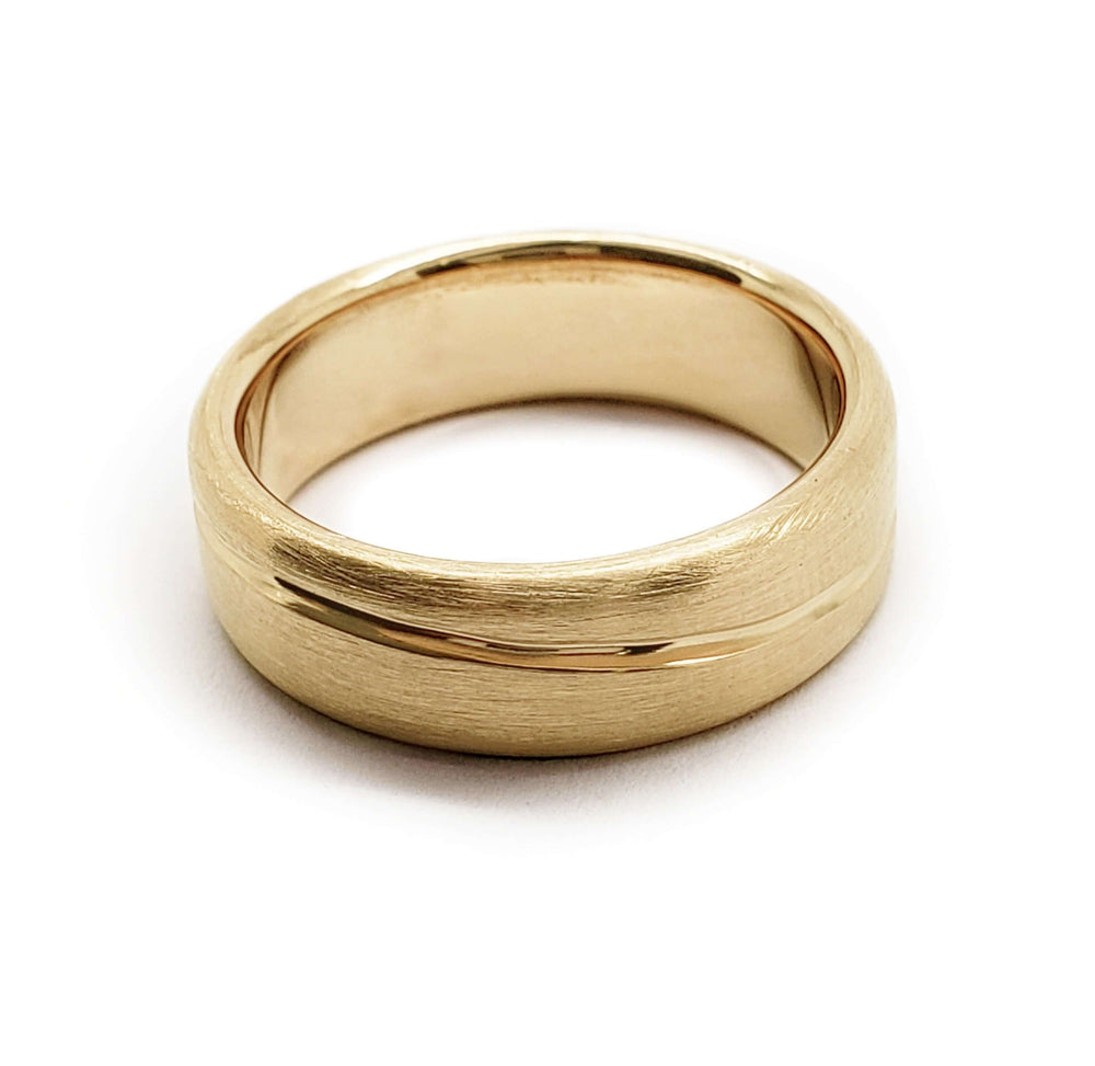 Flat profile 14kt yellow gold wedding ring with brushed finish and carved accent