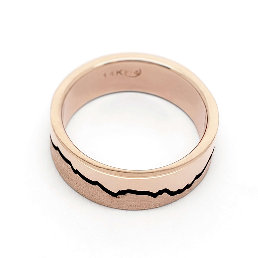 Flat profile rose gold wedding band with blackened mountain silhouette and textured finish