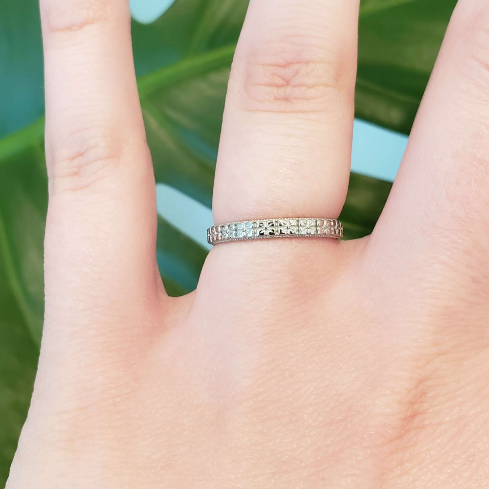 Floral millgrain wedding ring in white gold shown on a hand