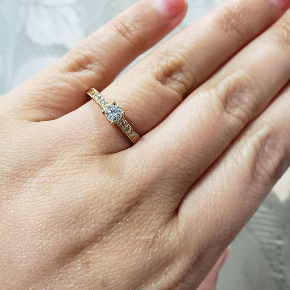 Yellow gold diamond engagement ring with pave shoulders shown on a woman's hand
