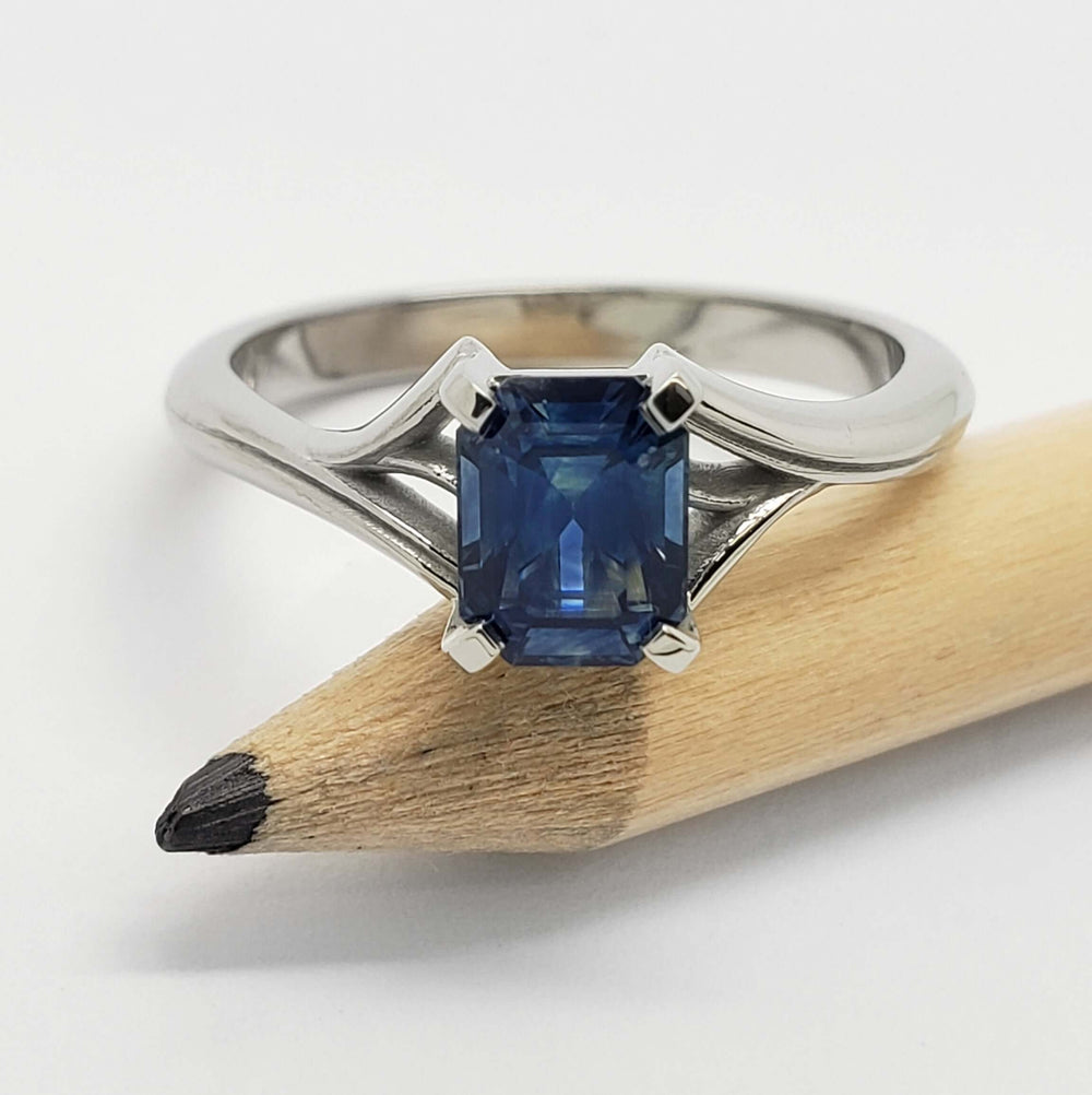 Front view of 14kt white gold ring with blue Montana sapphire, shown with pencil