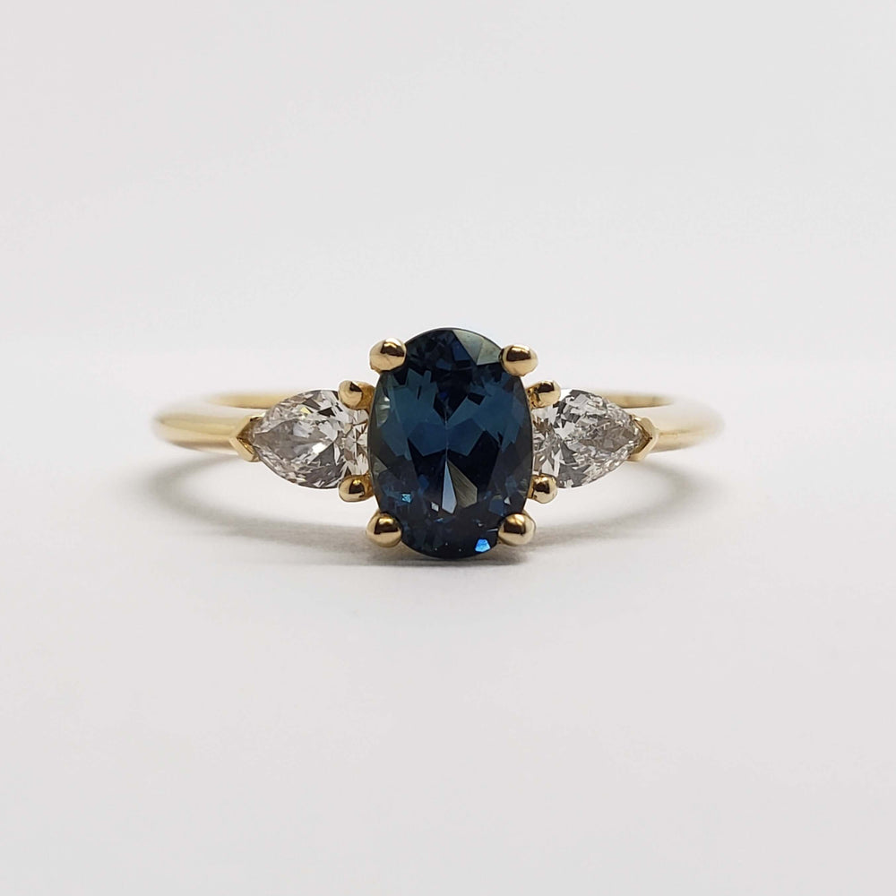 Front view of 14kt yellow gold ring with oval blue sapphire and two pear lab diamonds