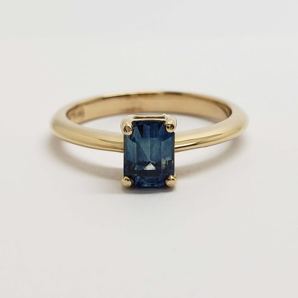 Front view of 14kt yellow gold engagement ring with blue emerald cut Montana sapphire