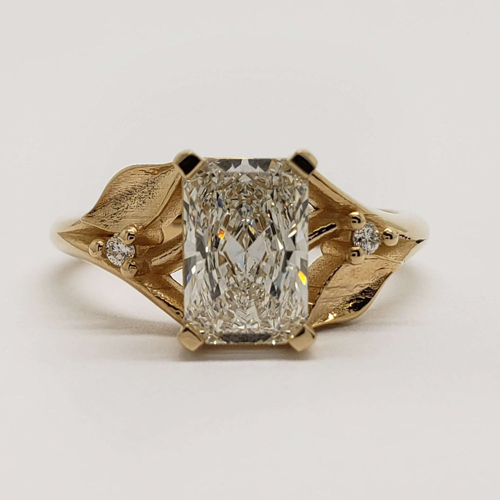 Front view of 14kt yellow gold engagement ring with radiant lab diamond and leaf accents
