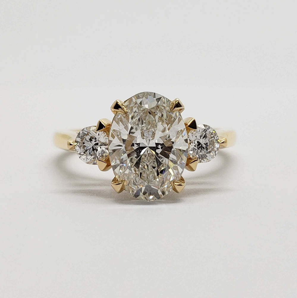 Front view of 14kt yellow gold ring with oval lab-grown diamond and two round lab diamonds