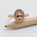 Front view of 14kt yellow gold ring with oval peach sapphire and diamond halo, engraved floral details