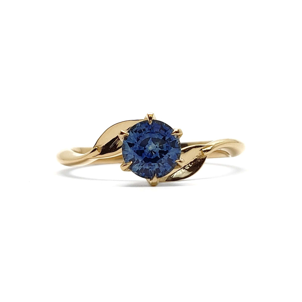 Front view of 14kt yellow gold ring with blue Montana sapphire and leaf accents